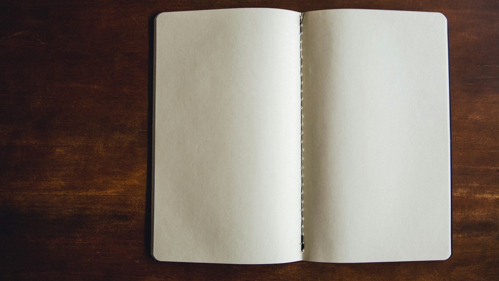 Cuaderno abierto en blanco sobre una mesa de madera para practicar gramática francesa