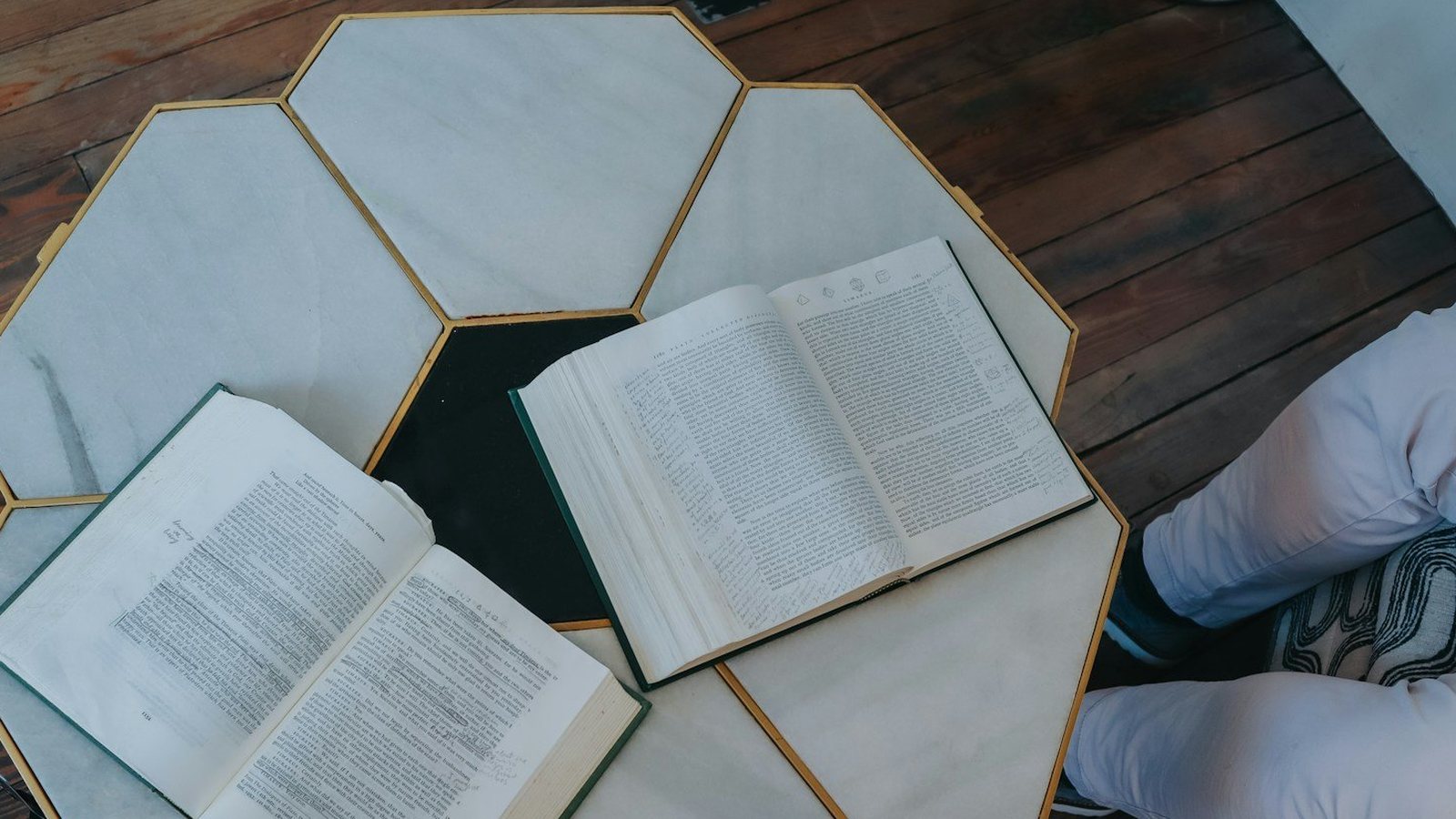 Dos libros abiertos sobre una mesa hexagonal de mármol, listos para comparar textos