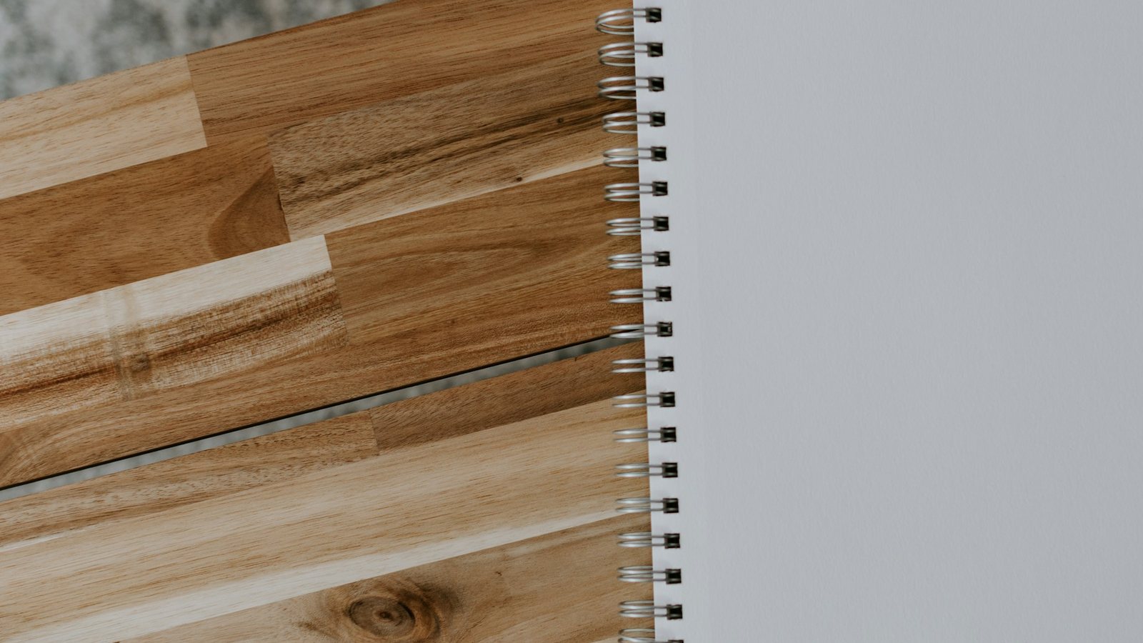Libreta de espiral con la hoja en blanco sobre una mesa de madera clara